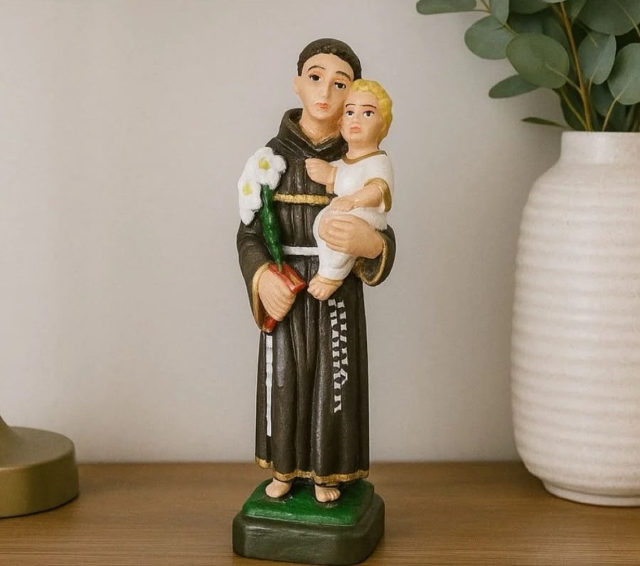 Estátua de Santo Antônio segurando o Menino Jesus, lírios e a Bíblia, com hábito marrom e detalhes dourados